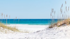 A beach with sand and sparse grass, leading to the ocean. - Coastal Haven by Gulf and Sound (Pensacola Beach)