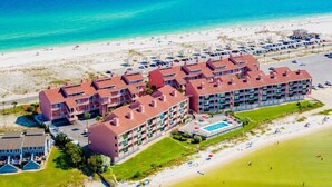 A beachfront hotel with multiple buildings, a pool, and a beach area. - Coastal Haven by Gulf and Sound (Pensacola Beach)