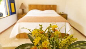 A hotel room with a bed, a nightstand, and a bedside table with a lamp. - FINCA ENCANTO QUINDIO (Armenia)