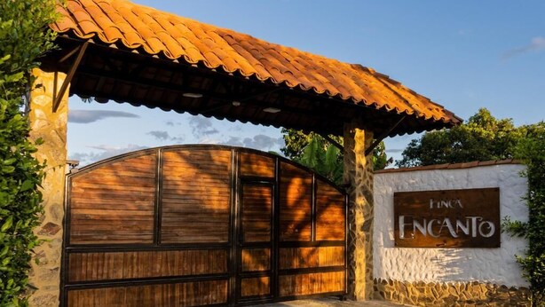 A gated entrance with a wooden gate and a sign that reads "FINCA ENCANTO". - FINCA ENCANTO QUINDIO (Armenia)