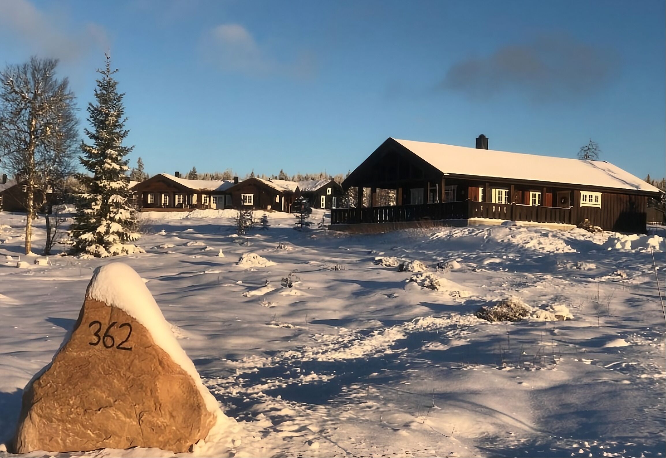 Een besneeuwd landschap met een chalet en een rots met nummering.