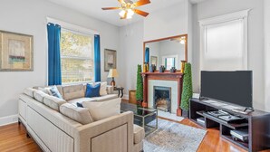 Un salon comprenant un canapé, un téléviseur, une cheminée et un ventilateur de plafond.