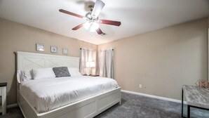 Une chambre à coucher avec un lit, un ventilateur de plafond, une table de chevet et une table.
