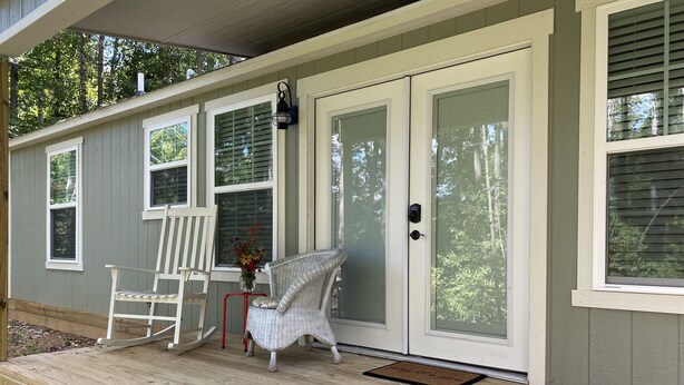 A covered porch with a bench and a chair, a door with a doormat, and windows with blinds. - Private lake, cozy cottage near hiking, waterfalls, rafting, state parks, Helen (Demorest)