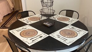 A round dining table with four chairs, a wire basket centerpiece, and placemats with wood grain designs. - Private lake, cozy cottage near hiking, waterfalls, rafting, state parks, Helen (Demorest)