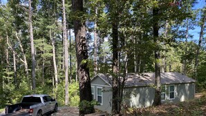 A small cabin with a number sign '575' in front, surrounded by tall trees and a parked truck. - Private lake, cozy cottage near hiking, waterfalls, rafting, state parks, Helen (Demorest)