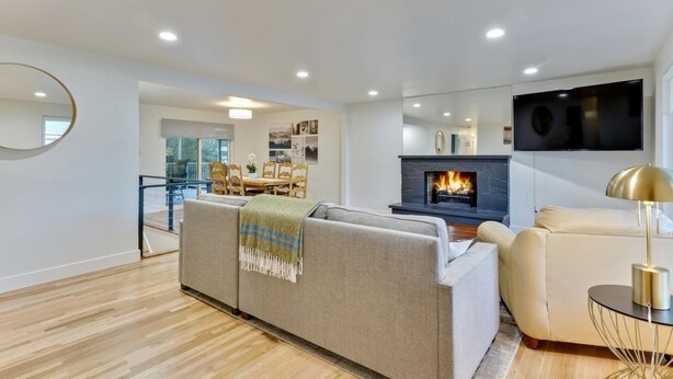 A modern living room with a fireplace, a sofa, a TV, and a dining area.