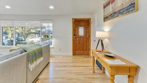 A modern living room with a sofa, a wooden door, a table with a lamp, and a painting on the wall.