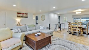 A modern living room with a sofa, coffee table, and dining area with chairs.