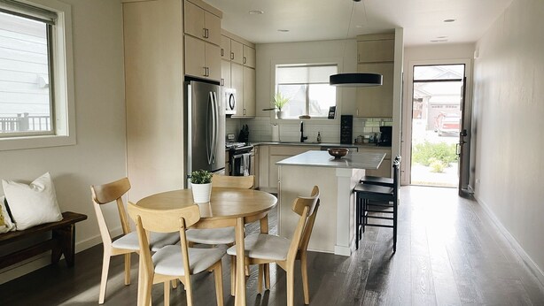 A modern kitchen with a dining area, featuring a central island, wooden chairs, and a built-in refrigerator. - Modern Guest Suite, 3 Miles from Downtown Bozeman (Bozeman)