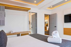 A modern hotel room with a bed, a desk, a wardrobe, and a TV.
