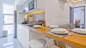 Una cocina moderna con armarios blancos, un microondas integrado y una mesa de comedor de madera dispuesta con platos y cubiertos.
