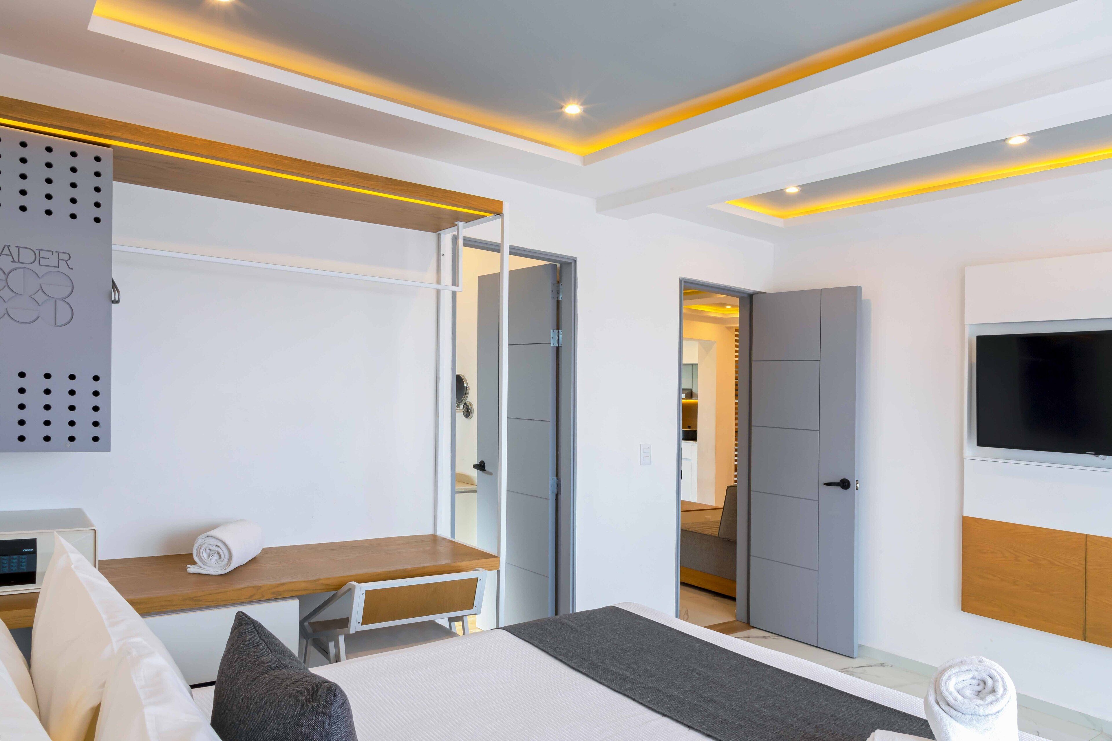 A modern hotel room with a bed, a desk, a TV, and a wardrobe.