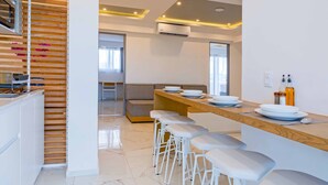 Una cocina moderna con una pared de acento de madera, una zona de bar integrada con taburetes y un área de estar al fondo.