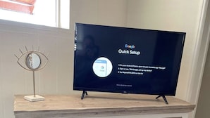 A television on a wooden cabinet with drawers and louvered doors.