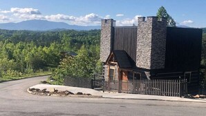 A stone building with a wooden door and a small porch, surrounded by a fence and a road. - The Log Castle~Stunning Mountain Views~Hot Tub (Sevierville)