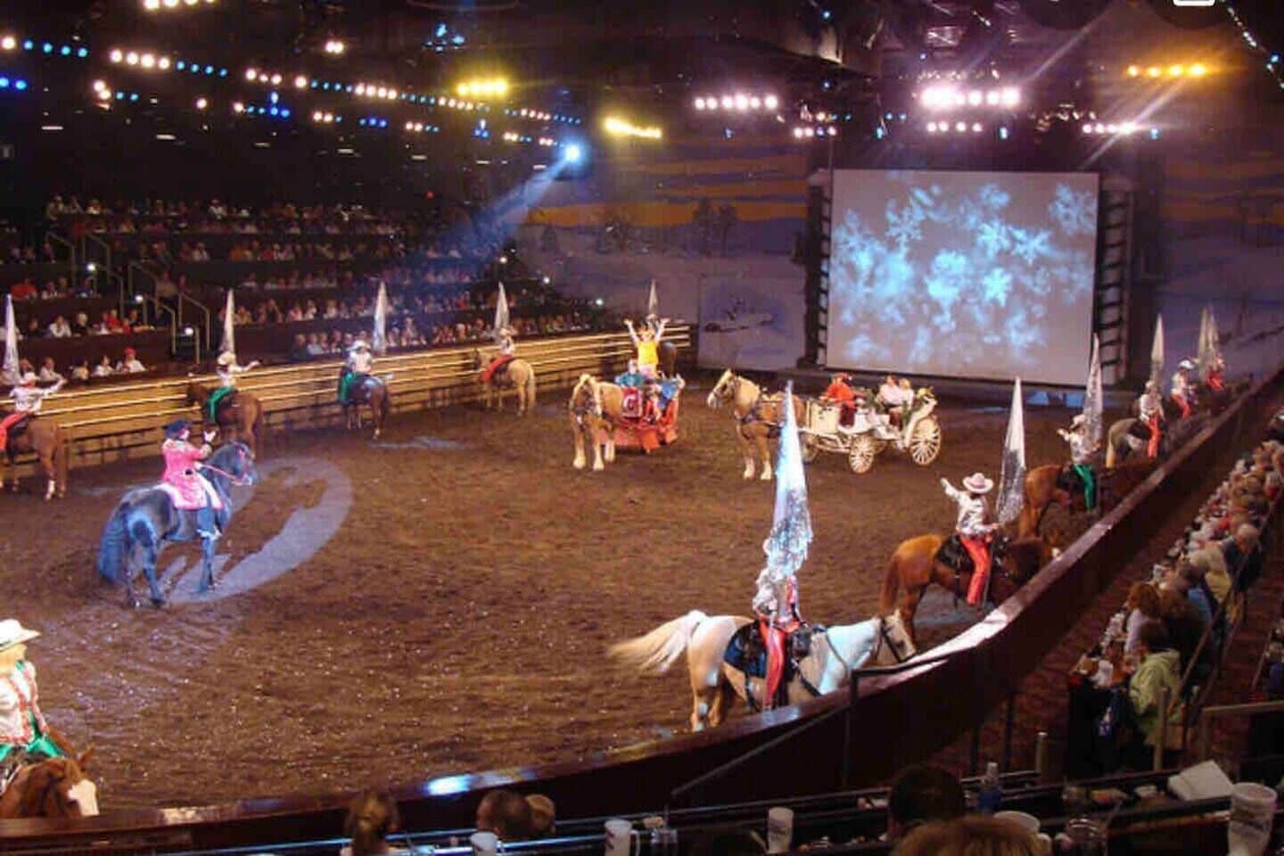 Una arena de rodeo con caballos y jinetes actuando.
