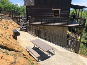 A rustic cabin with a picnic table and a small staircase leading to a deck.