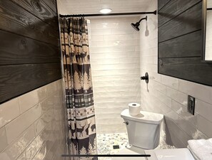 A bathroom with a shower, toilet, and a patterned curtain.