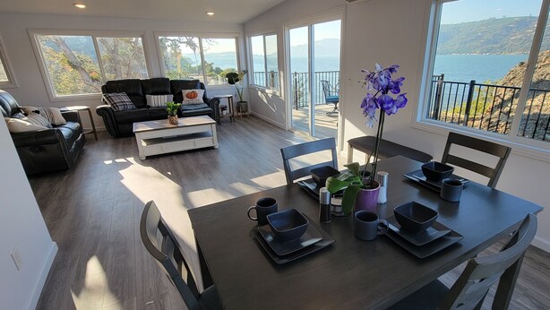 Un amplio salón con una mesa de comedor lista para cuatro personas, un sofá y un balcón con vistas al mar.