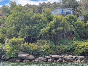 A house surrounded by dense greenery and a rocky shoreline. - Majestic Rock House (Clearlake)