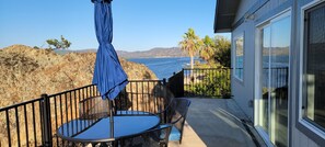 A balcony with a table and chairs, overlooking a rocky coastline and the ocean.