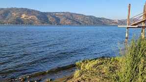 Un lago con un muelle que se adentra en el agua, rodeado de colinas y vegetación.