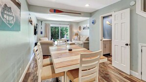 Un comedor con una mesa y sillas de madera, un sofá y una puerta que da a una cocina.