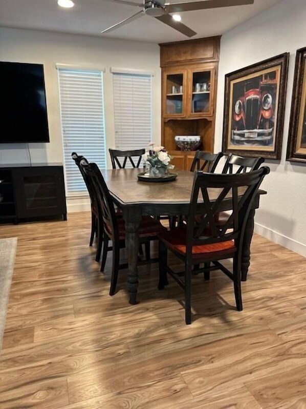 A dining area with a wooden table and chairs, a ceiling fan, and a television on the left. - Whole home in Zinfandel Country (Lodi)