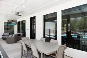 Un patio exterior con una mesa de comedor, sillas y sofás de mimbre.