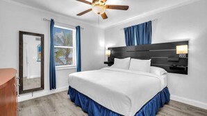 A bedroom with a bed, a ceiling fan, a nightstand, a mirror, and a window with curtains. - Spectacular Ocean View Corner Apartment! (Hollywood)
