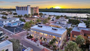 A hotel with multiple floors, a parking lot, and a view of the ocean at sunset. - Spectacular Ocean View Corner Apartment! (Hollywood)