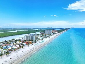 A coastal hotel with a beachside location, featuring multiple buildings, a sandy beach, and a clear view of the ocean.