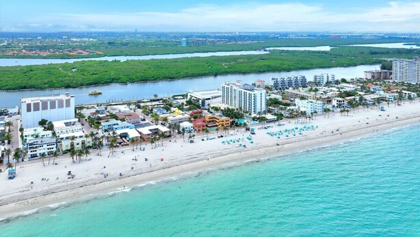 An aerial view of a coastal resort with a beachfront, hotel buildings, and a marina. - Ultimate Beach Getaway! (Hollywood)