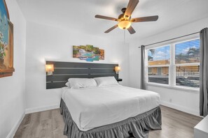 A bedroom with a bed, a ceiling fan, a nightstand, a window with blinds, and a painting on the wall. - Amazing 1st Floor Apartment Just Steps to Beach (Hollywood)