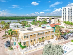 A hotel with a flat roof, multiple balconies, and a parking area with cars. - Amazing 1st Floor Apartment Just Steps to Beach (Hollywood)