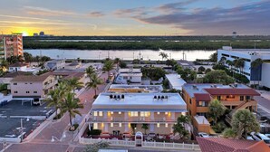 A coastal cityscape with a prominent hotel, a marina, and a sunset over the water.
