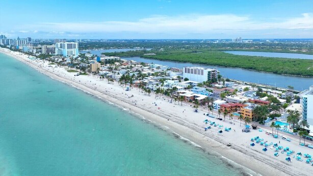 An aerial view of a coastal city with a beach, hotels, and a marina.