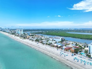 Luchtbeeld van een kustplaats met een strand, hotels en een jachthaven.