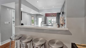 Een moderne keuken met een centraal eiland, barstoelen en uitzicht op de straat.