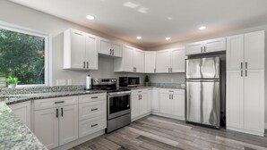 A modern kitchen with white cabinets, stainless steel appliances, and a granite countertop. - River Retreat W/ HOT TUB/ Game room (Bristol)