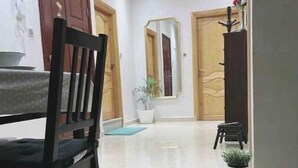 Un interior moderno con un área de comedor que presenta una mesa y sillas de madera, una planta en maceta y un espejo en la pared.