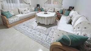 Un salón acogedor con una mesa redonda, dos sofás y una alfombra estampada.