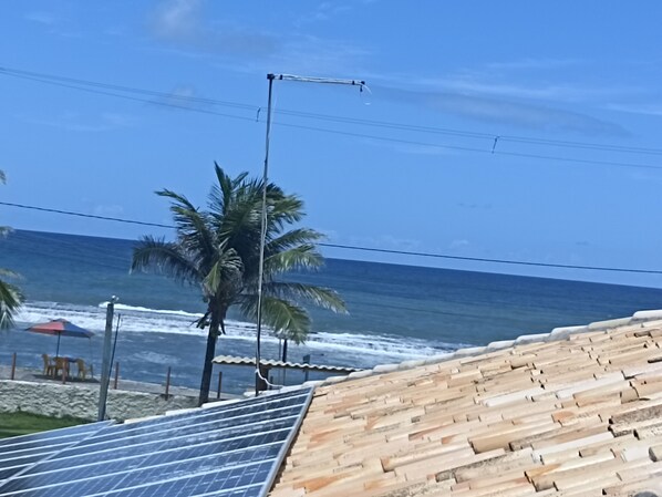 Vista de playa con palmeras, olas del océano e instalación de paneles solares.
