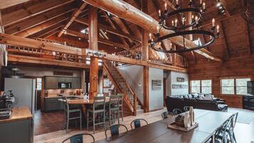 A spacious log cabin interior with a dining area, kitchen, and living room.