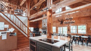A spacious kitchen with a central island, wooden beams, and a stone wall. - High Meadows Secluded Luxury Lodge, 20+ Acres, Hot Tub, Private Trails, Wifi (Rockbridge)
