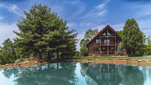A log cabin with a large deck and a pond in front. - High Meadows Secluded Luxury Lodge, 20+ Acres, Hot Tub, Private Trails, Wifi (Rockbridge)
