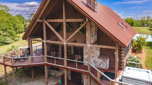 A log cabin with a stone chimney, a deck with outdoor seating, and a hot tub. - High Meadows Secluded Luxury Lodge, 20+ Acres, Hot Tub, Private Trails, Wifi (Rockbridge)