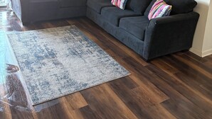 A modern living room with a sectional sofa, a ceiling fan, a large abstract painting, and a patterned rug.