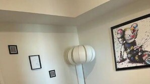 A bedroom with a bed, a white lamp, and a framed picture on the wall.